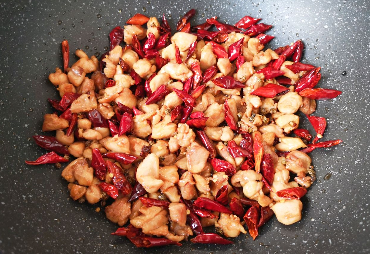 Stir-fry chicken thighs with dried red chilies and Sichuan peppercorns for flavor infusion.