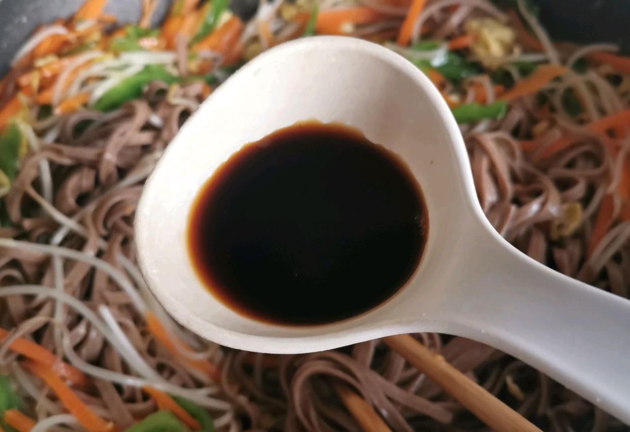 Add noodles to pan, pour soy sauce.