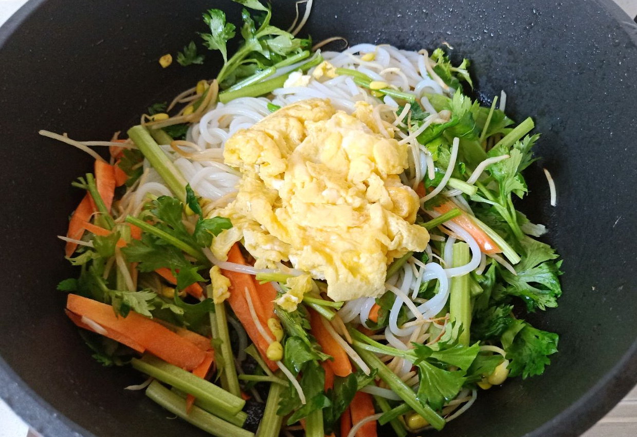 Stir-fry soaked rice noodles, veggies, and scrambled eggs together over high heat quickly.