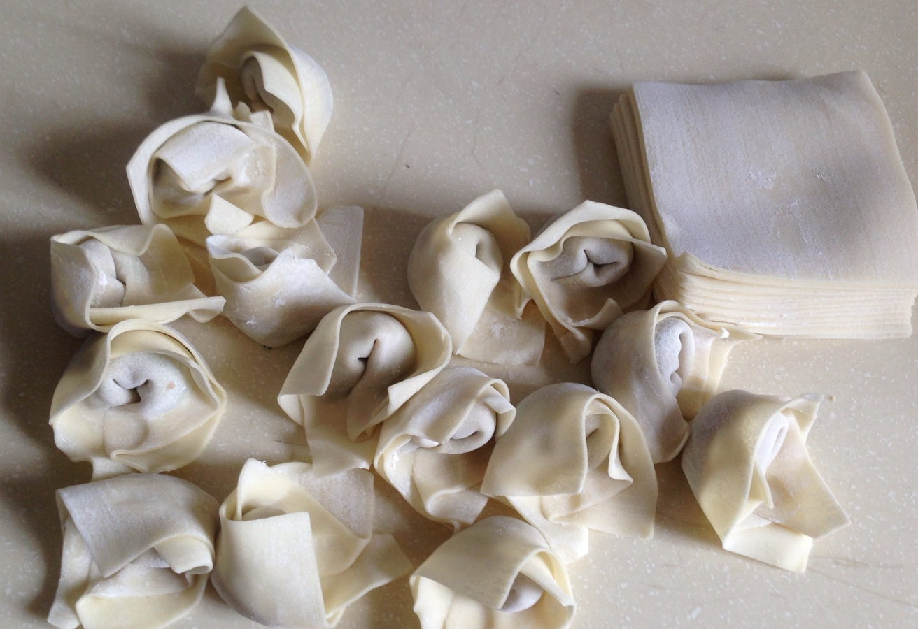 Guide to wrapping wontons: Fill, fold diagonally to seal edges; fold other corners inward. Avoid overfilling for even cooking.