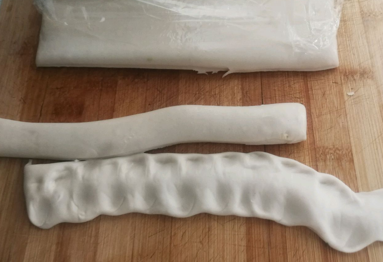 After resting, stretch dough into strips, bounce on table to length, tear middle to create wide noodles.