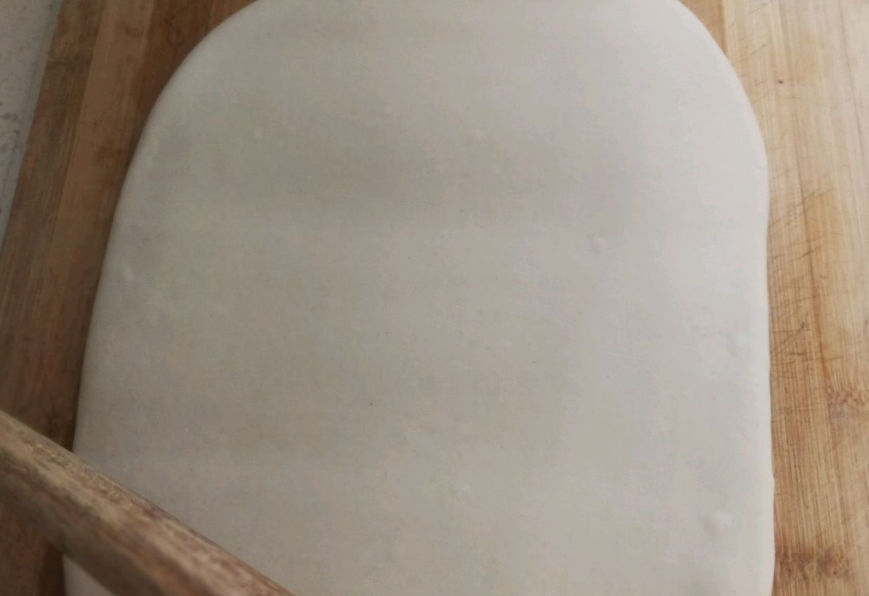 Roll out dough evenly on chopping board with rolling pin for uniform thickness.