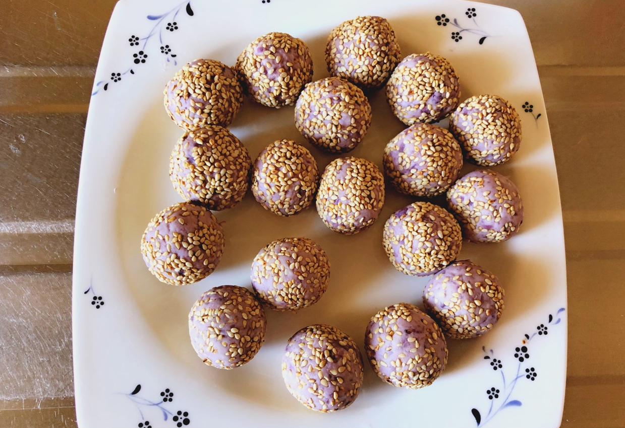 Roll purple sweet potato dough into balls and coat with white sesame seeds.