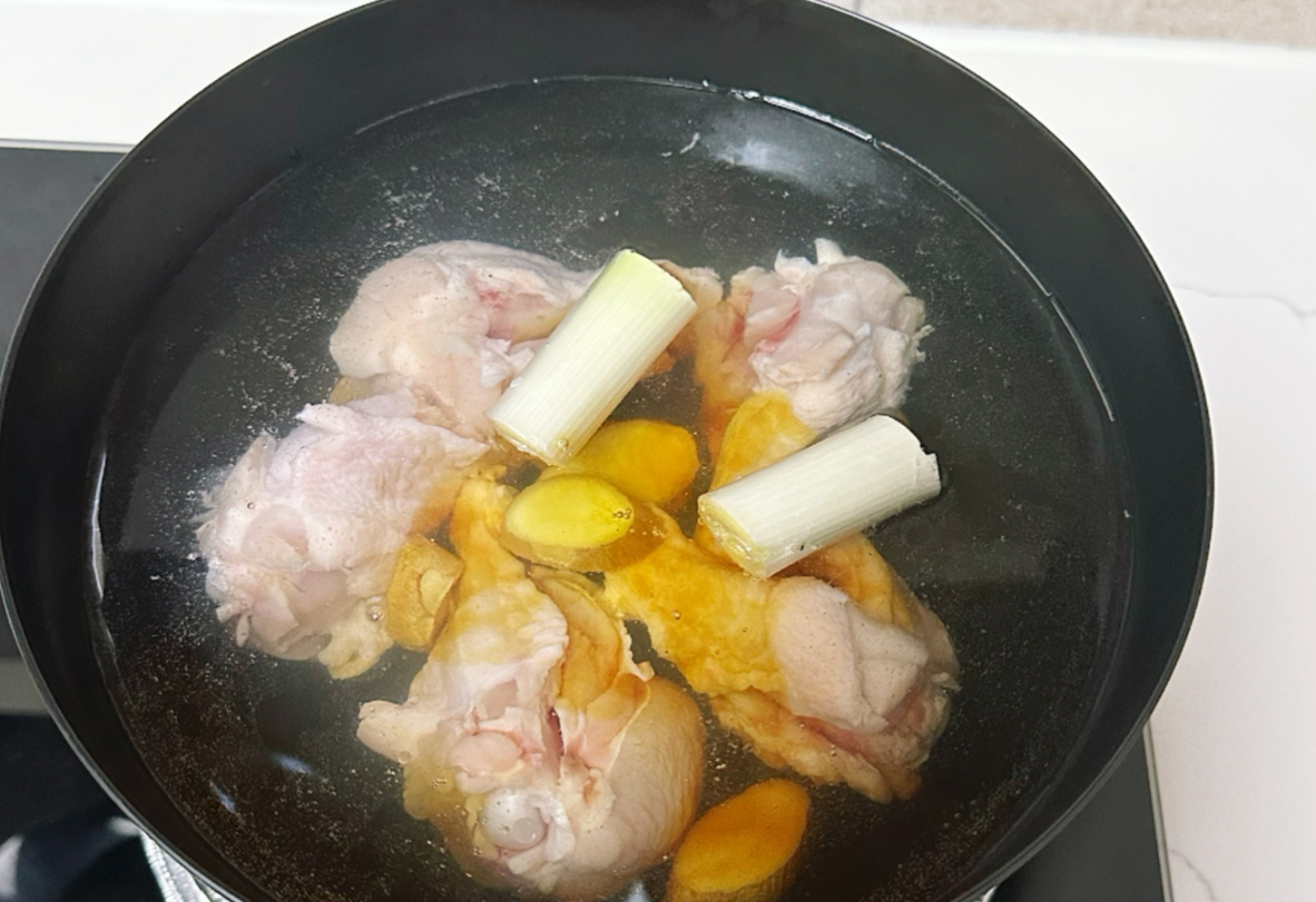 Boil chicken wings with ginger, green onion, wine, and soy sauce for flavorful dish.