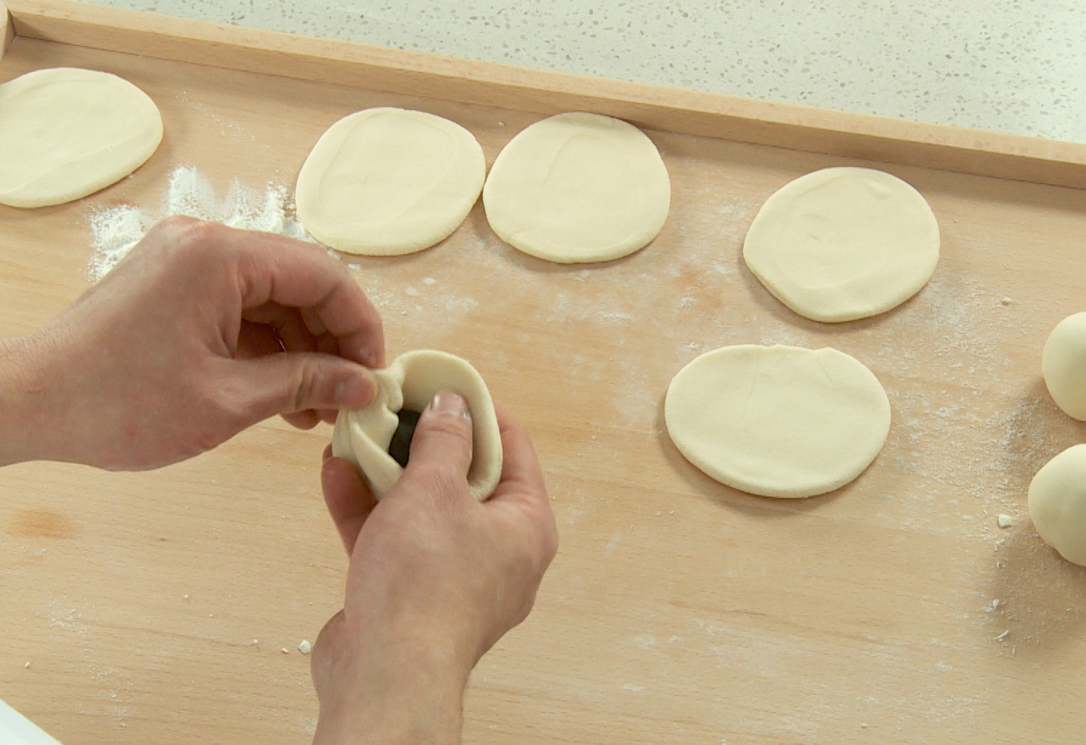 Steps to assemble Red Bean Buns: Place red bean paste in dough, pinch edges tightly.