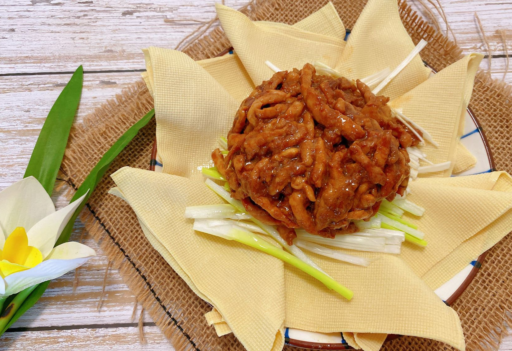 Pour stir-fried pork over shredded green onions on plate to serve.