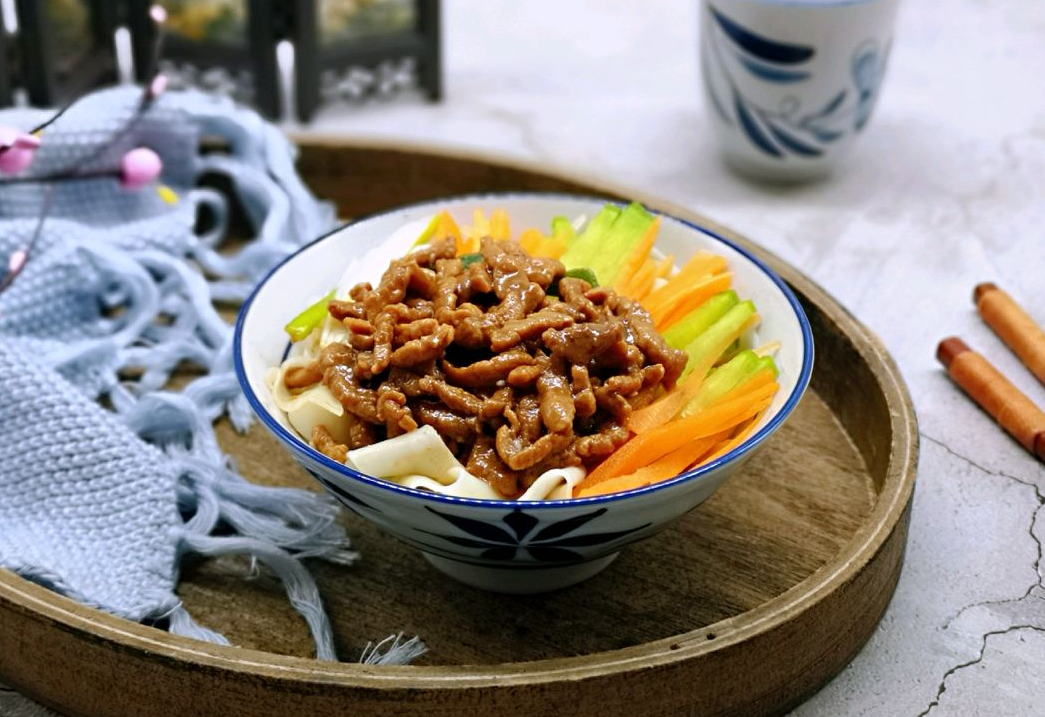 Layer julienned cucumber and carrot over noodles, then pour Zhajiang sauce for Zhajiangmian.