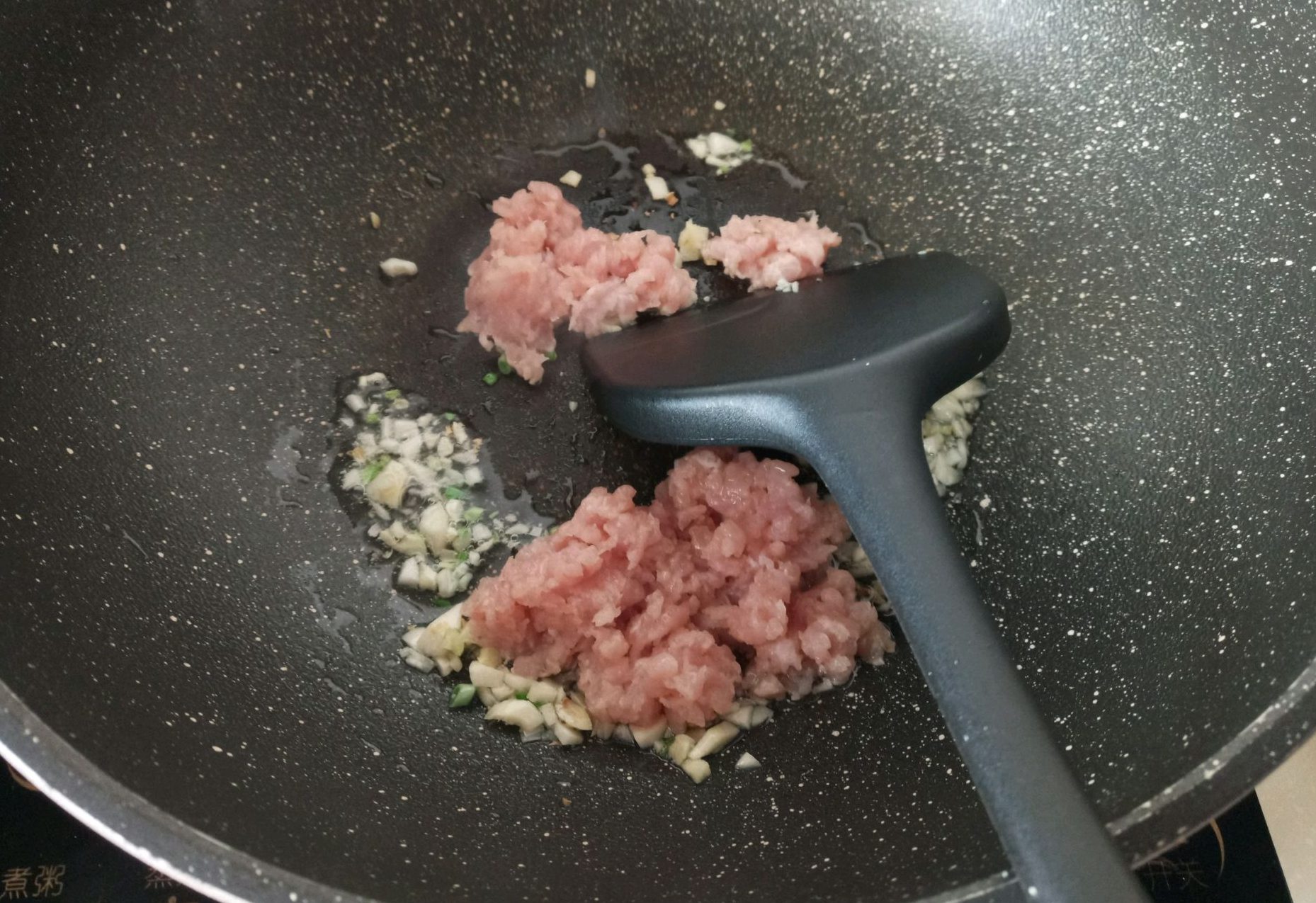 Stir-fry minced garlic, minced pork with oil in wok.