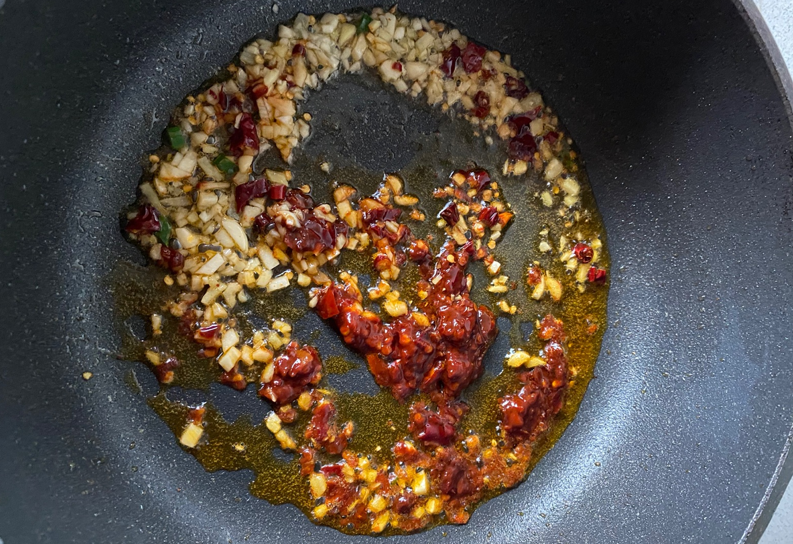 Pan fry ginger, garlic, chili, and doubanjiang in oil until fragrant.