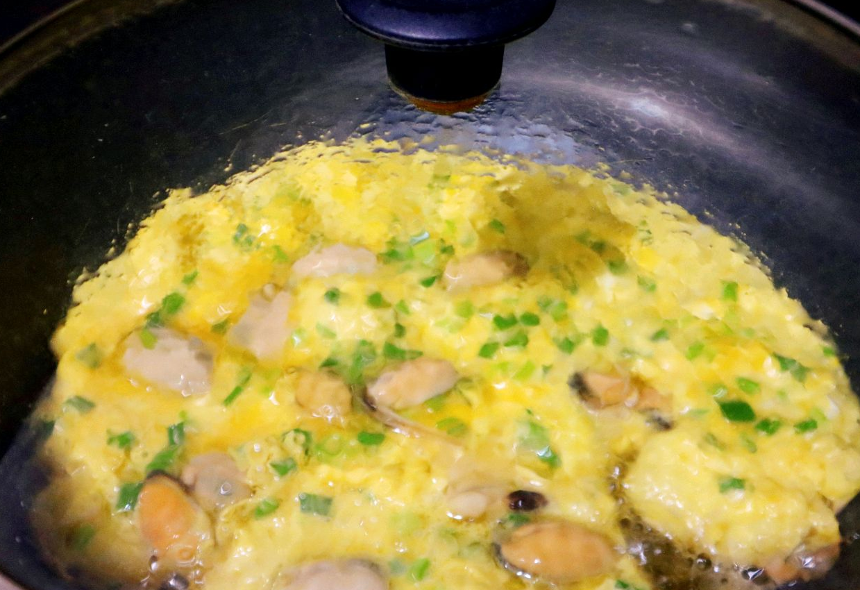 Cook scrambled eggs in hot oil, cover with lid, and cook until set.