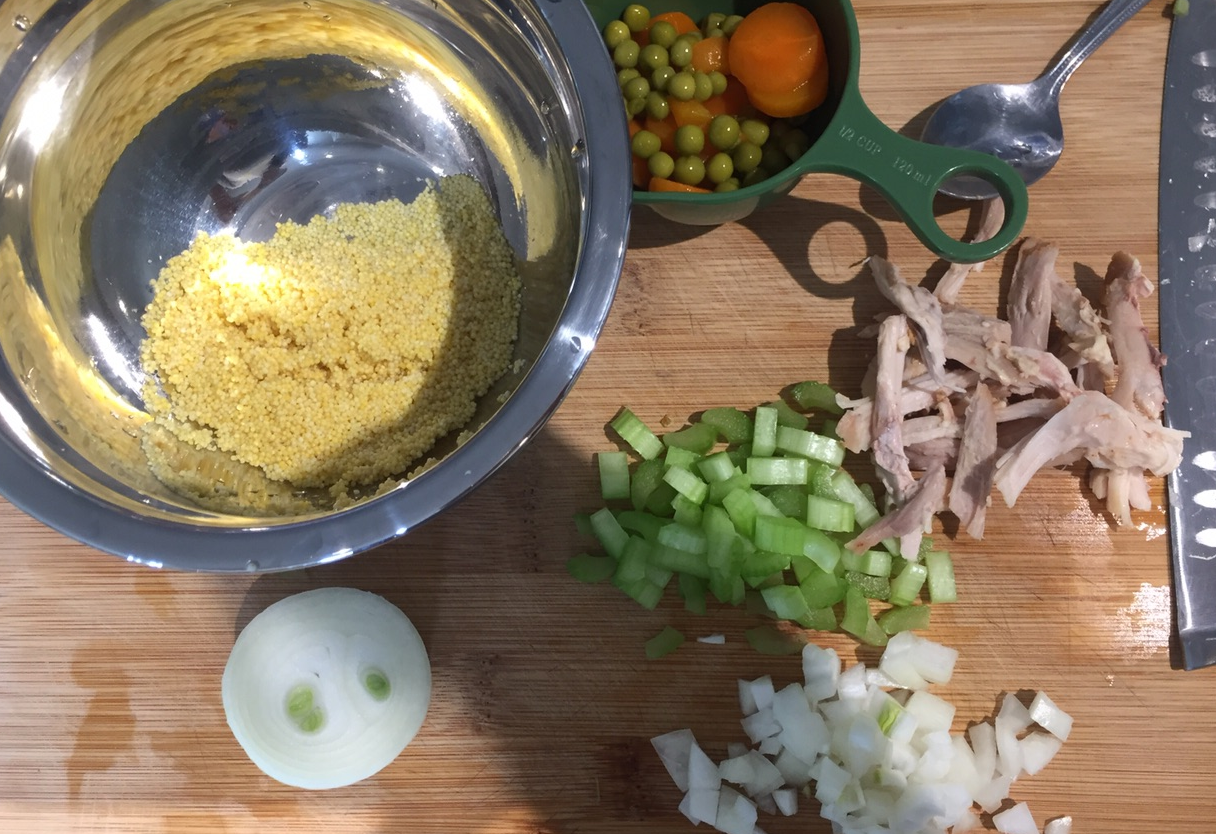 Prepare millet, chicken breast, celery, peas, onion, and carrot for cooking.