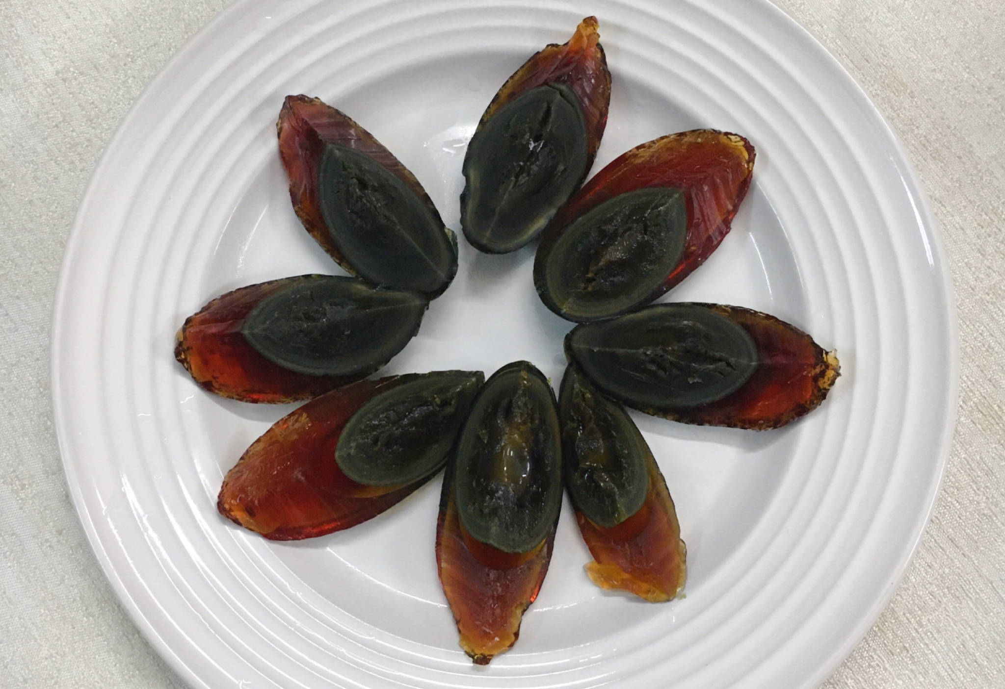 Cut cooled steamed century eggs in half and arrange on plate.