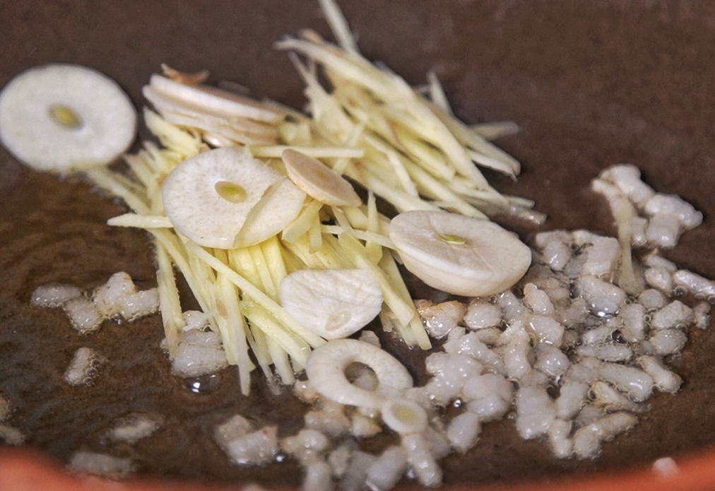 Add julienned ginger and sliced garlic to hot oil, stir-fry for fragrance.