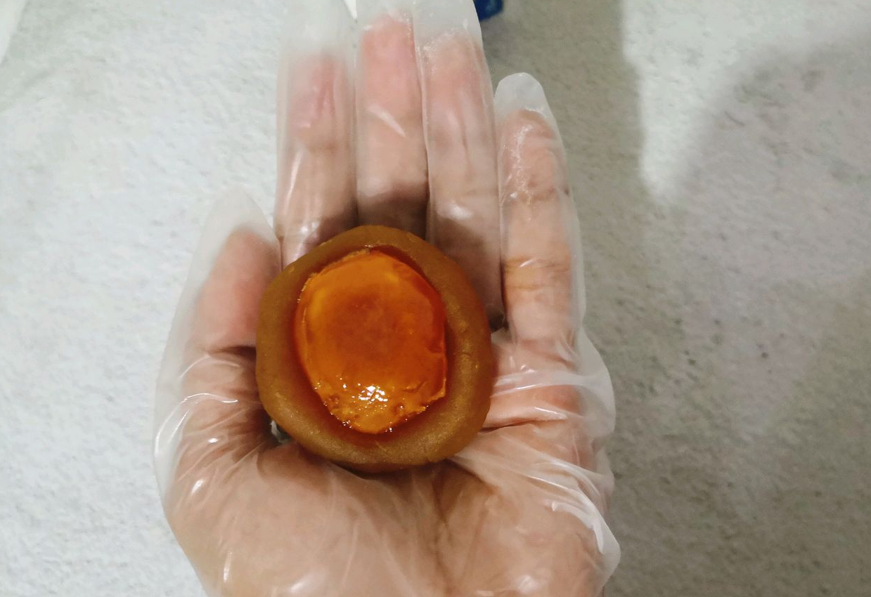 Shape red lotus seed paste into round disc, press indentation, place salted egg yolk.