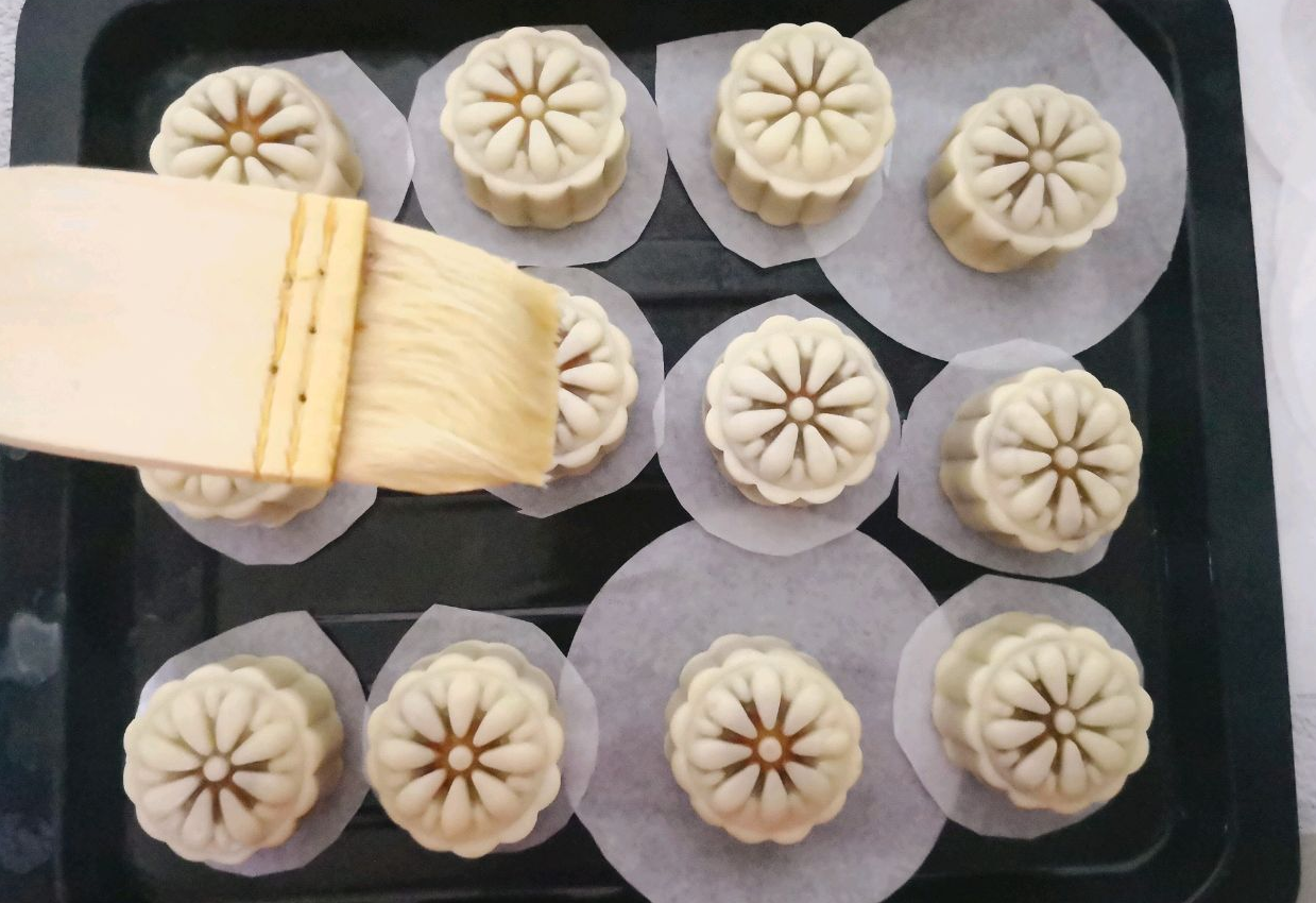 Brush the mooncakes with egg wash after 5 minutes, then bake.