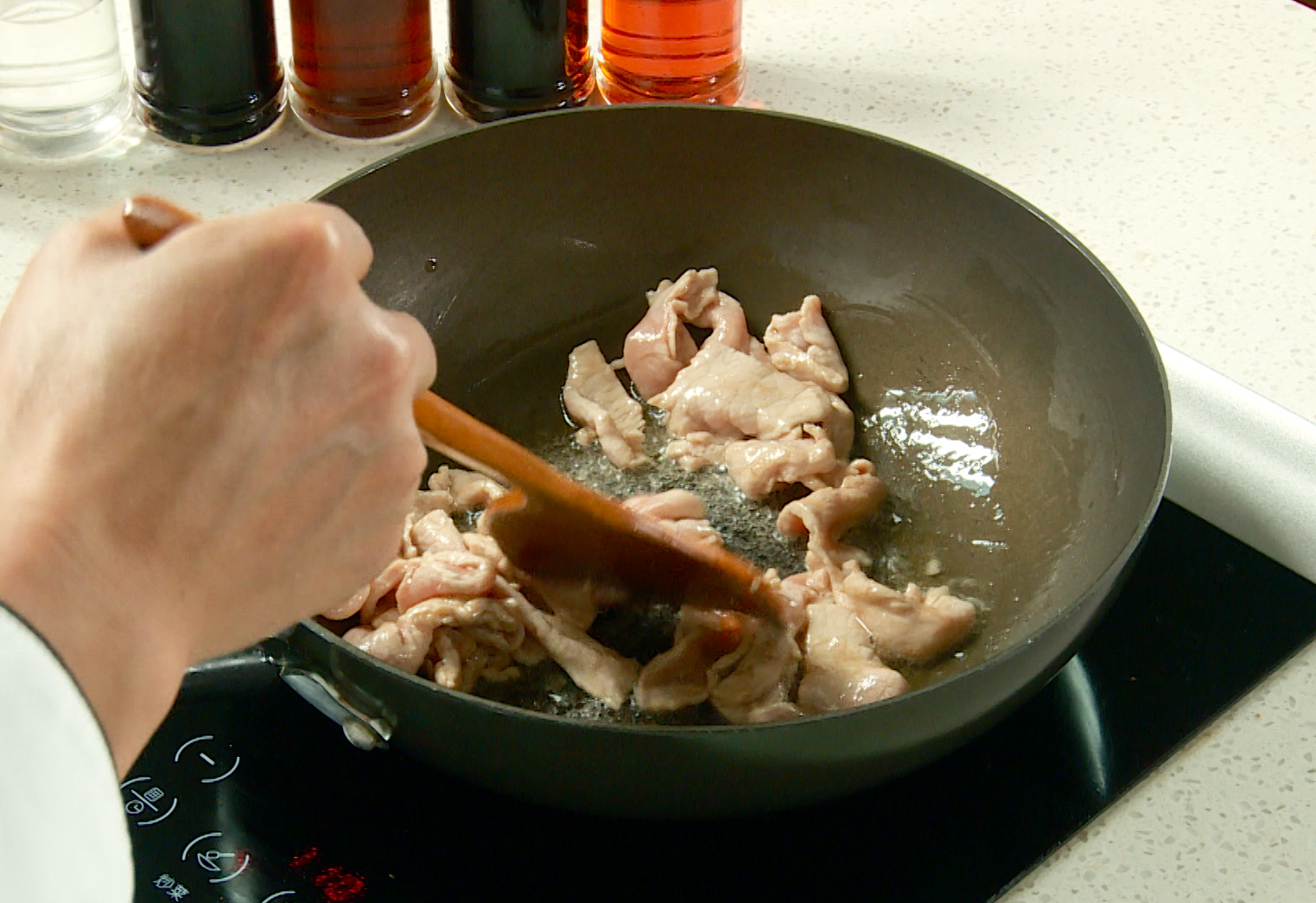 Cook marinated pork slices in hot oil until color changes.