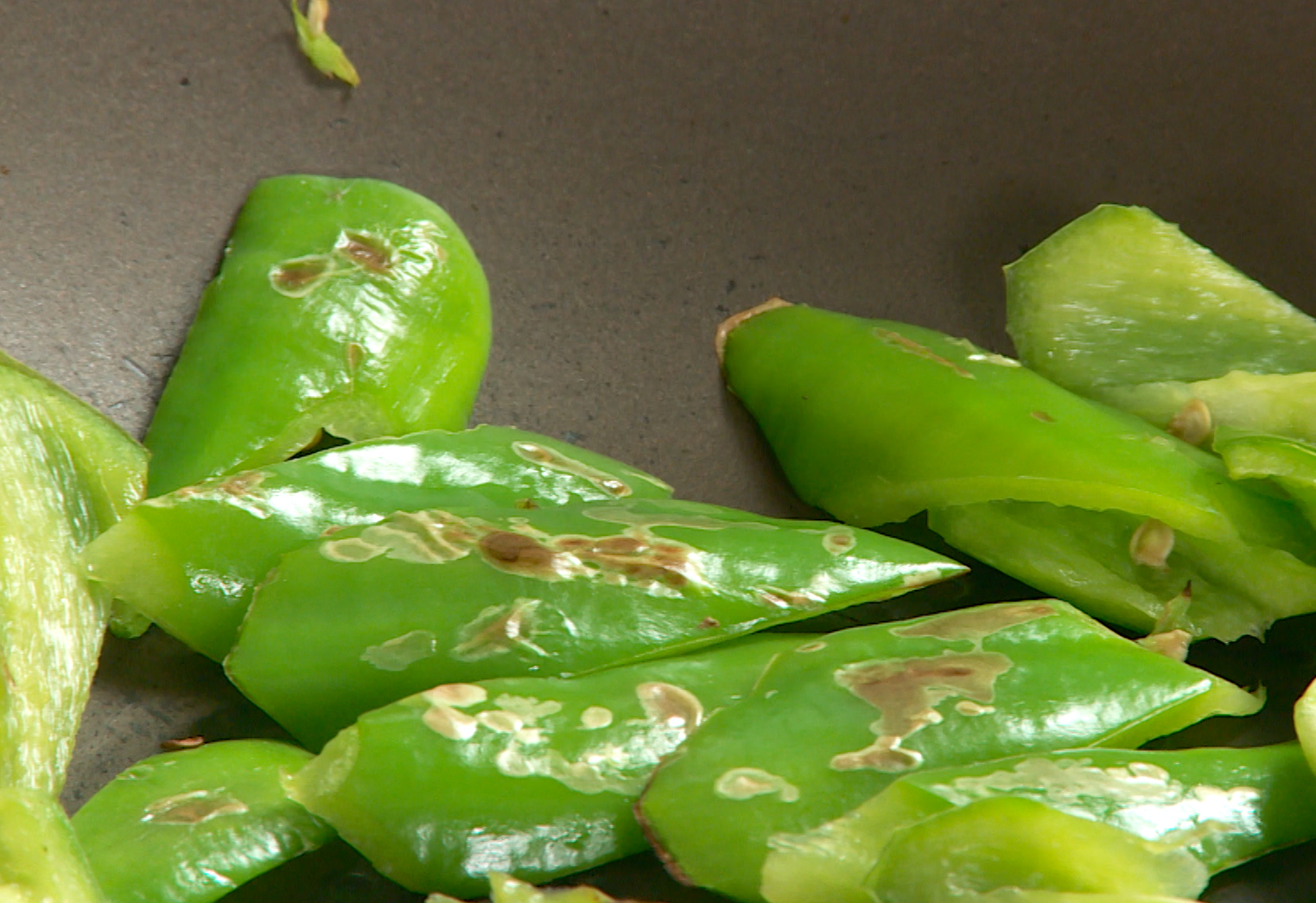 Roast green pepper chunks in a pan until wrinkled and golden.