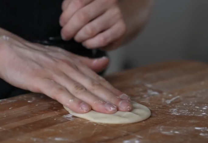 Divide rested dough into four parts, flatten one into oval shape.