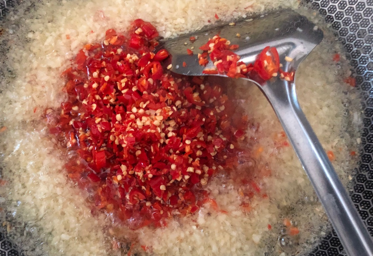 Add chopped bird's eye chilies to aromatic garlic; stir occasionally.