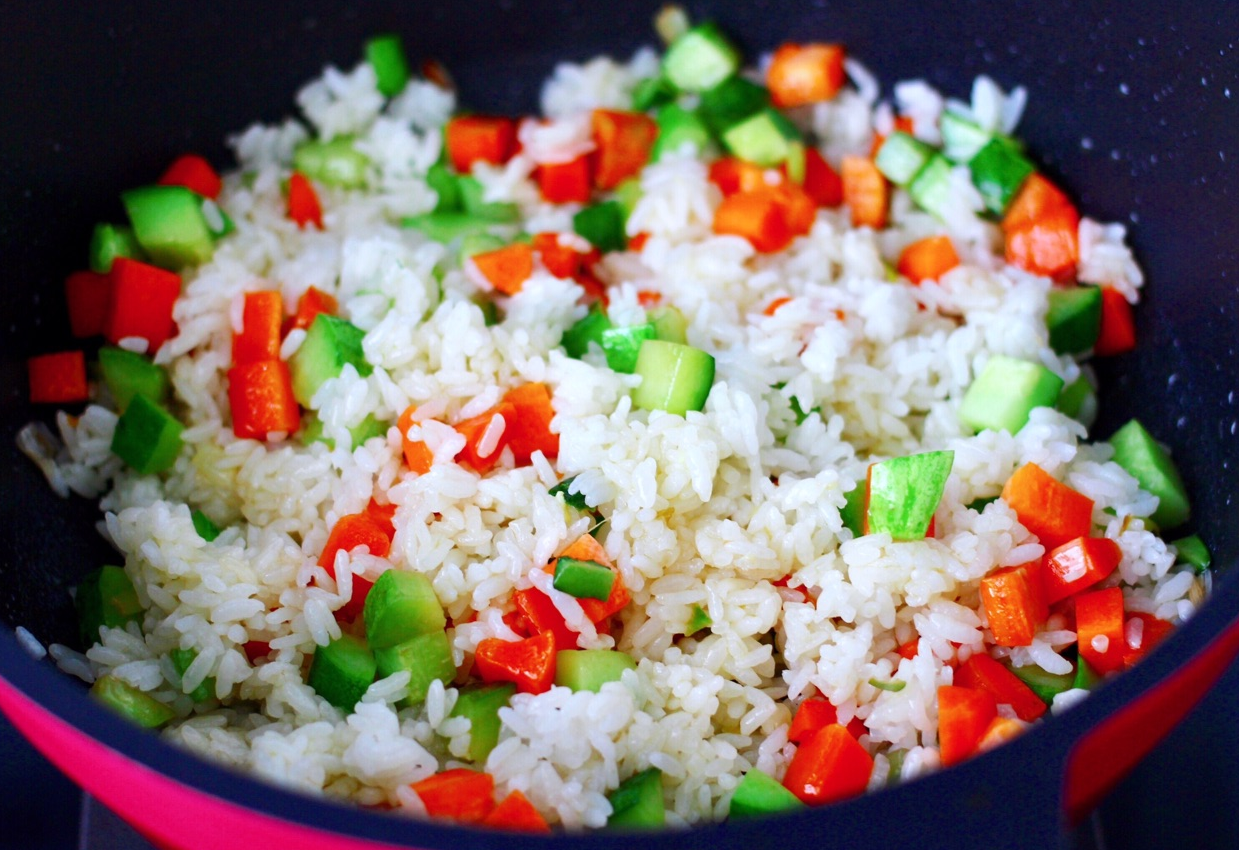 Stir-fry cooked vegetables with rice on high heat for a quick and well-mixed dish.