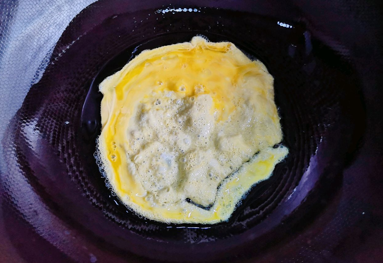 Instructions to pour beaten egg into a pan, spreading thinly to make a pancake.