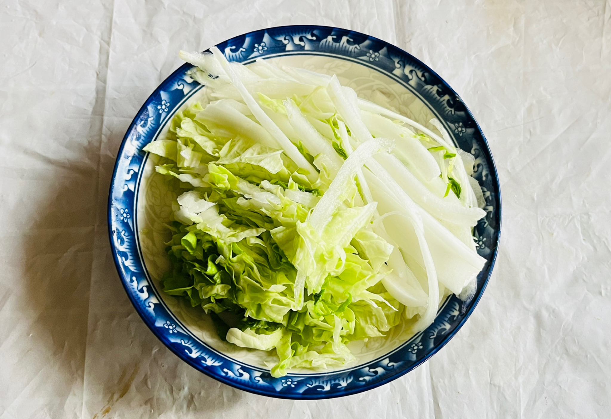 Shred cleaned Napa cabbage into thin strips for recipe.