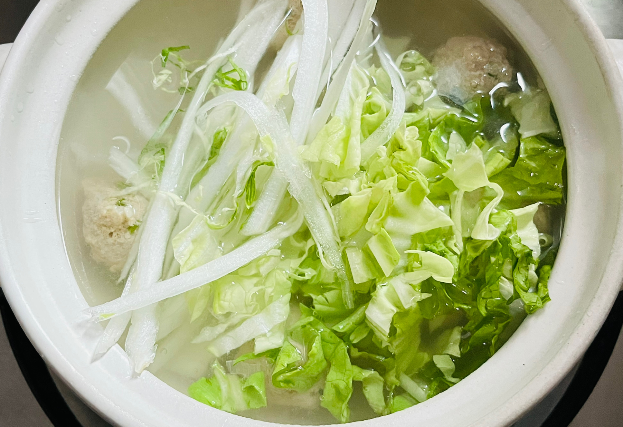 Simmer pork meatballs and Napa cabbage over low heat.