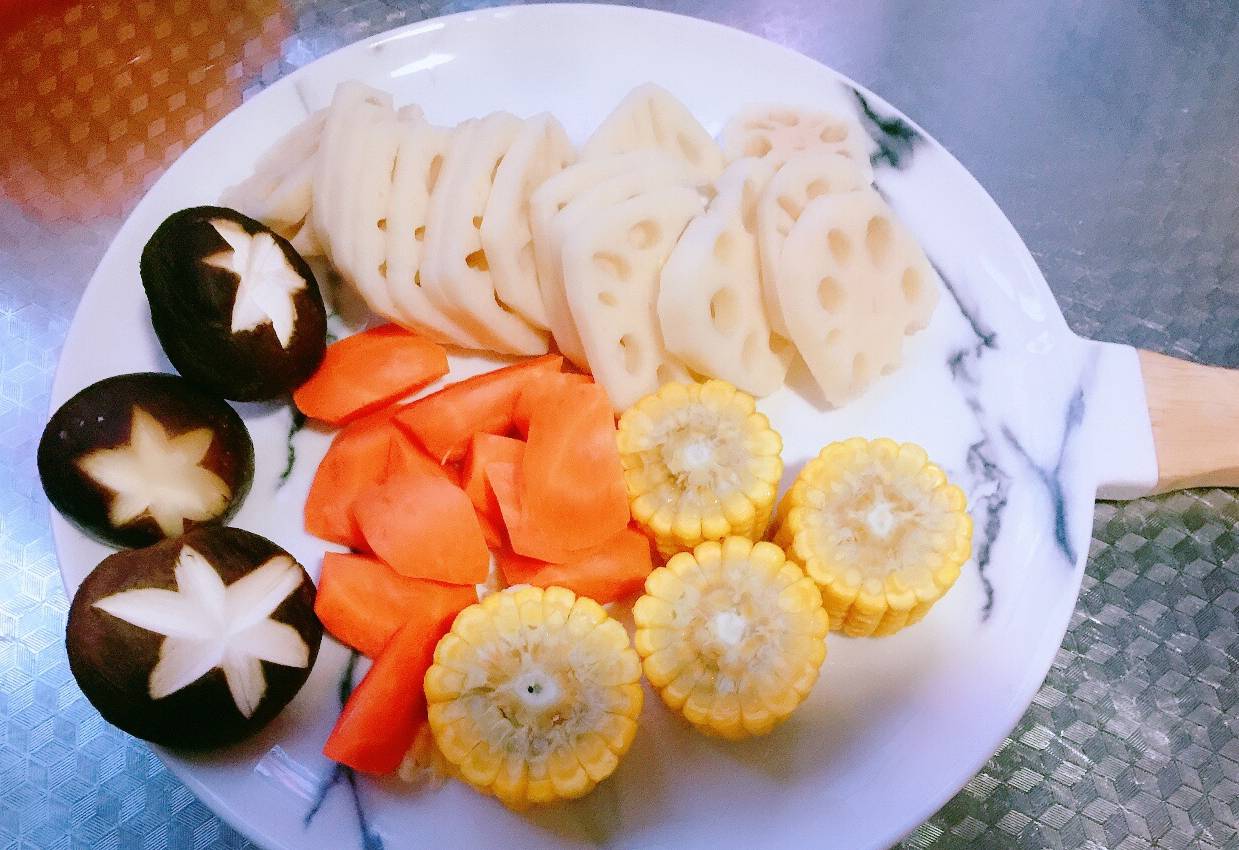 Prepare lotus root, corn, carrots, and shiitake mushrooms while cooking pork spine bones.