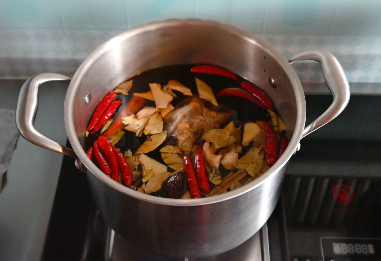 Boil water with spices, sugar, chili peppers, bean paste, soy sauces for flavor infusion.