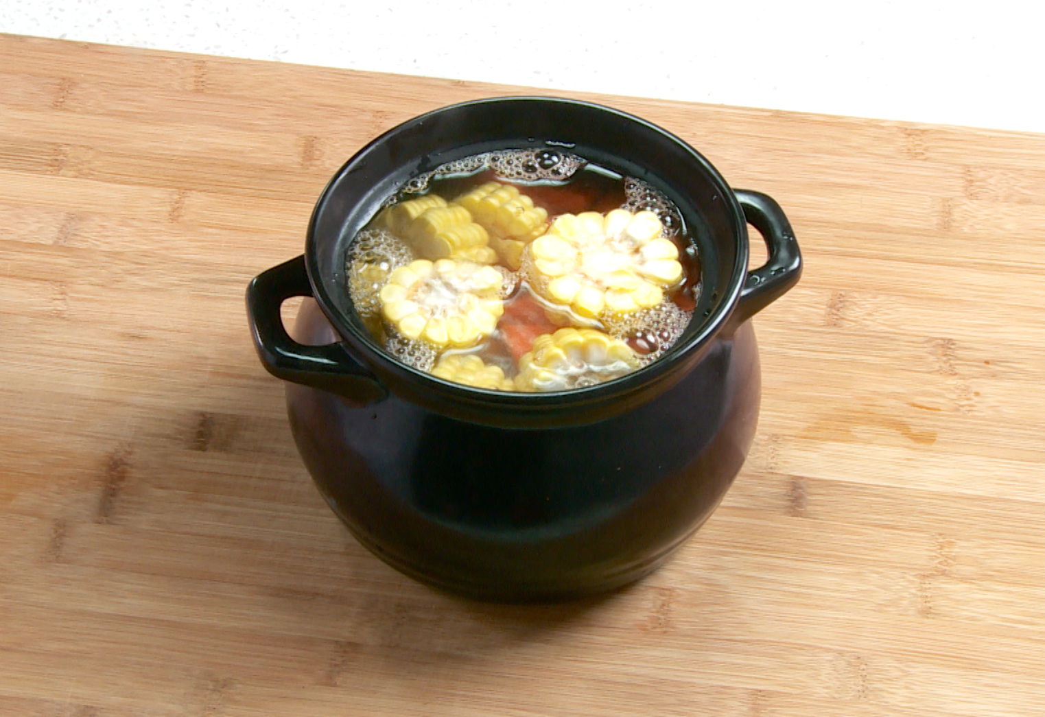 Cook pork rib soup with ginger, carrots, and corn in large pot for 1.5 hours.