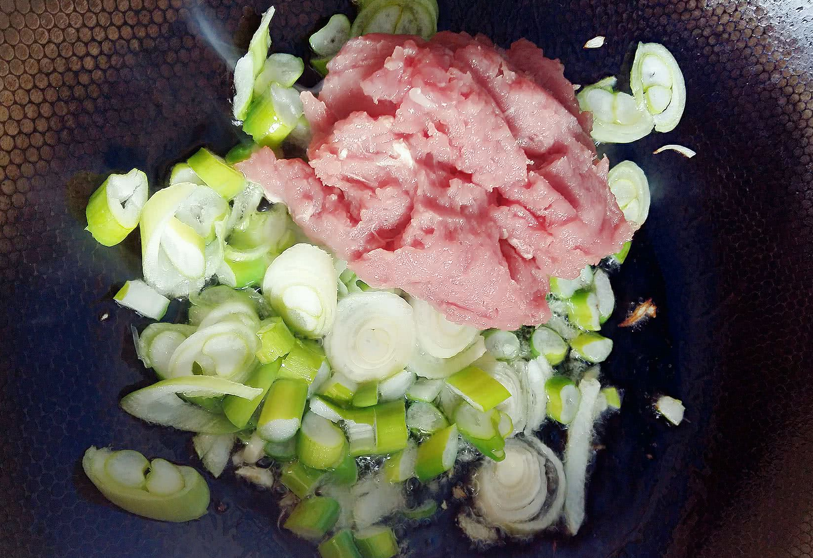 Heat oil in pan, add green onions, stir-fry, then add minced pork.