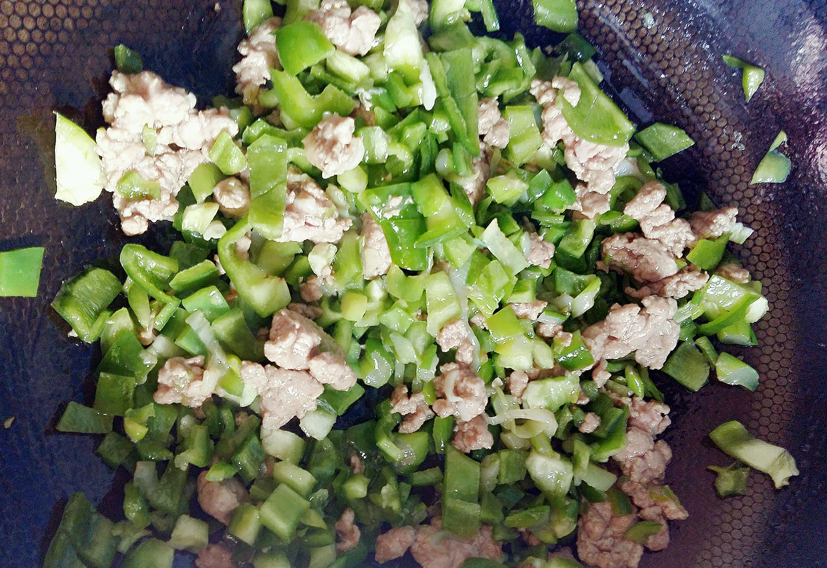 Stir-fry minced pork until color changes, then add green bell peppers.