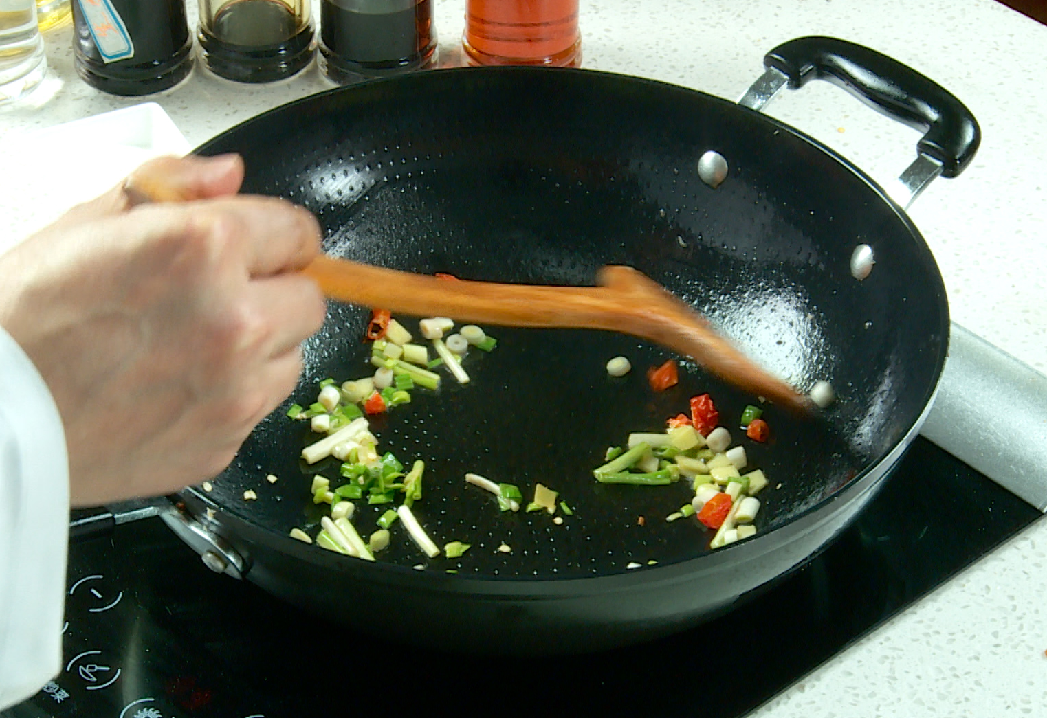 Sauté green onions, ginger, garlic leaves, and dried chili peppers until fragrant.