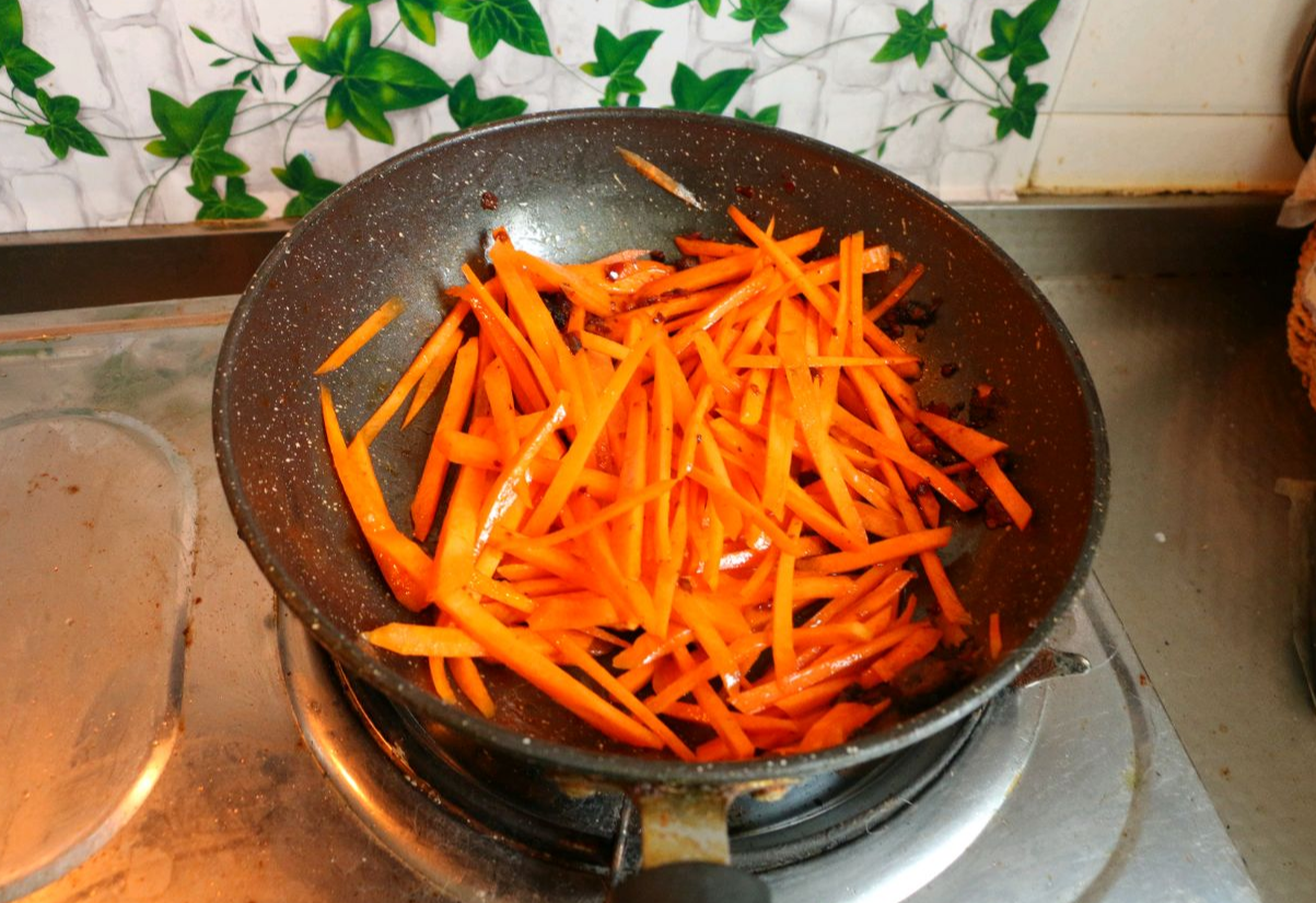 Stir-fry shredded carrots in pan for 3 minutes on high heat.