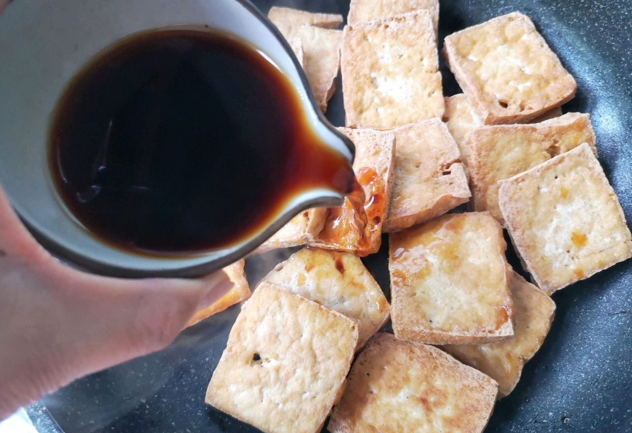 Place fried tofu in a pot and pour sauce over it.