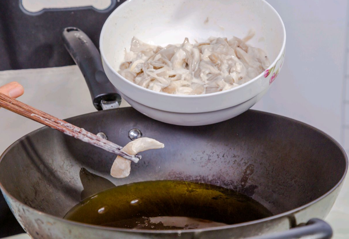 Use chopsticks to dip battered oyster mushrooms individually into hot oil to prevent sticking.