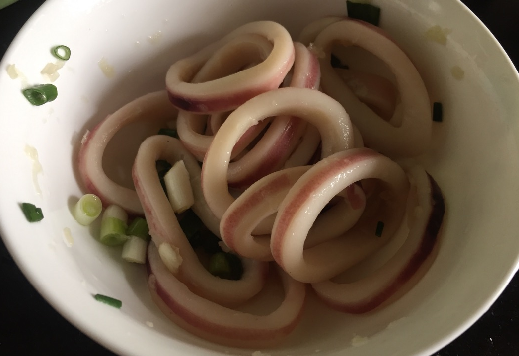 Chop spring onion and garlic, slice squid, marinate with cooking wine, salt, garlic, and spring onion.