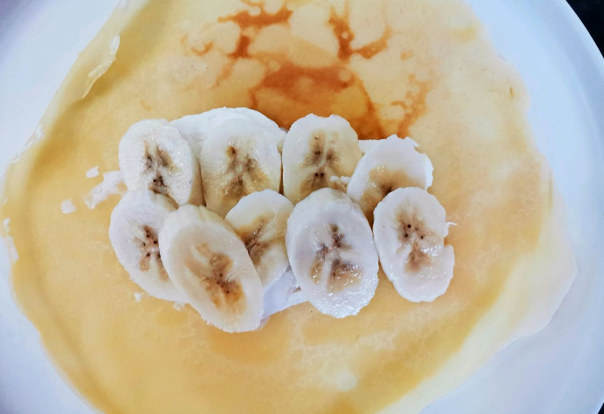 Top crepe with banana slices, sweeten with condensed milk.