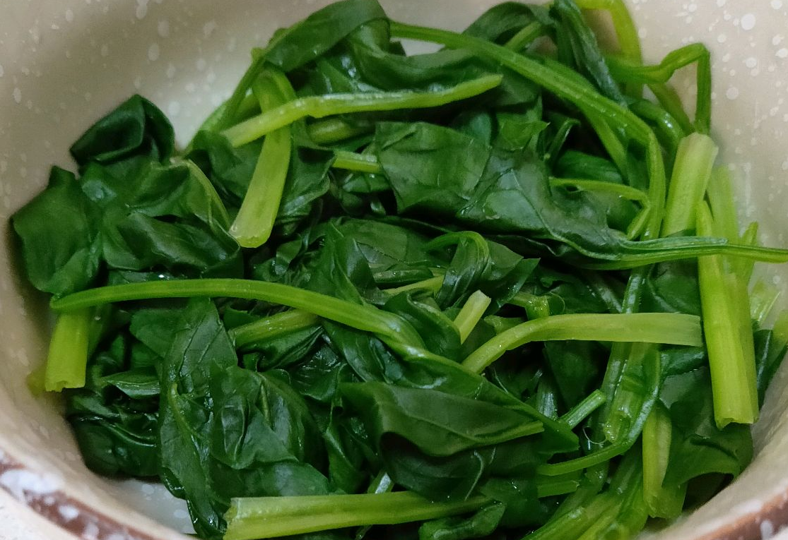 Rinsing spinach under cold water maintains its crisp texture after cooking.