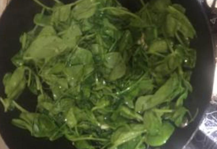 Stir-fry pea shoots over high heat.