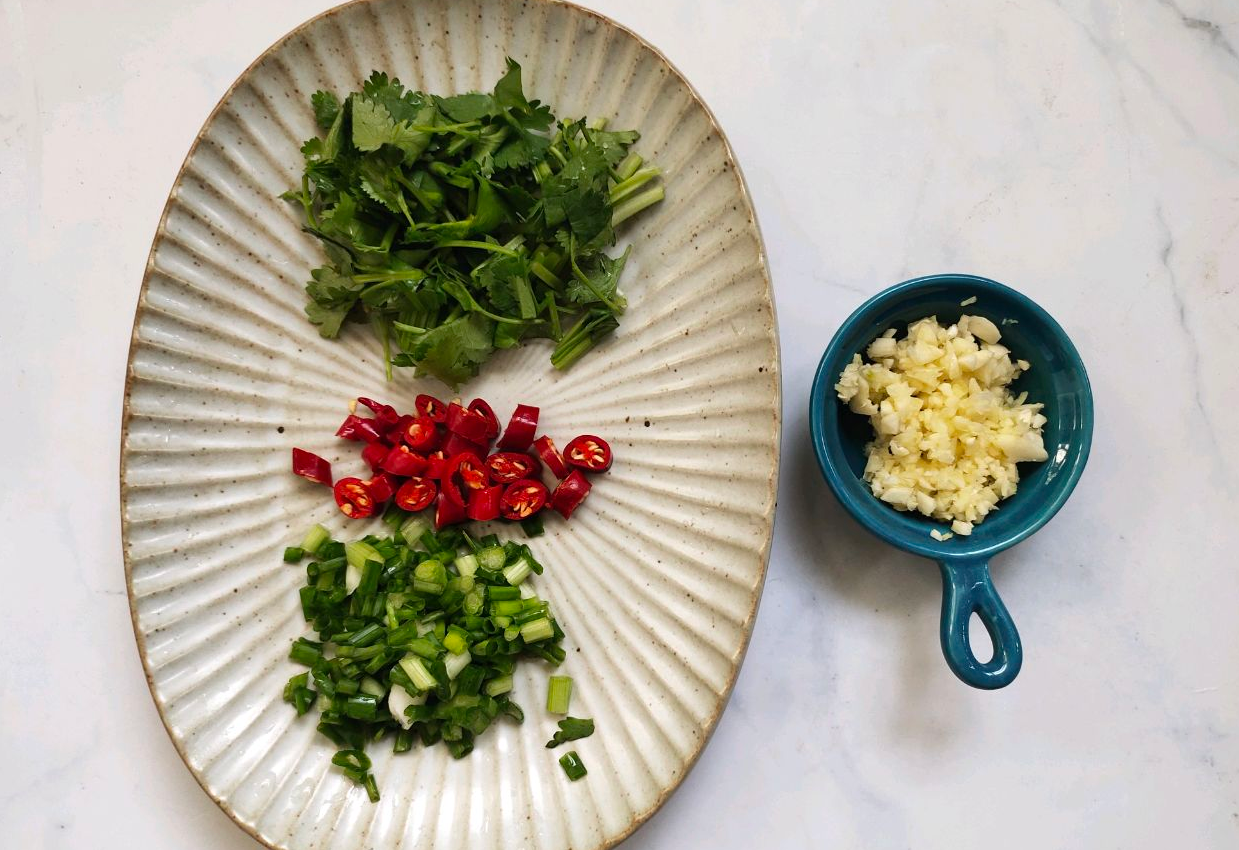 Prepare garnishes: Wash & chop 2 chili peppers, 2 scallions, 3 garlic cloves, and 2 cilantro sprigs.