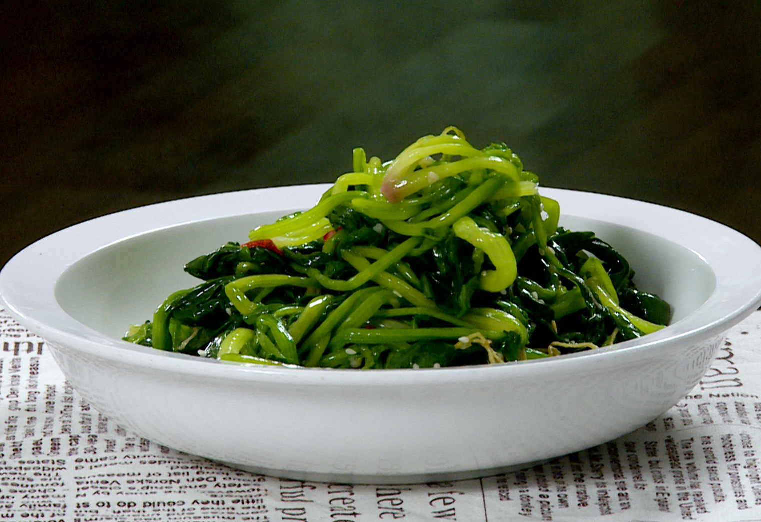 Serve spinach on plate, sprinkle with sesame seeds for a nutritious, flavorful dish. 🌿