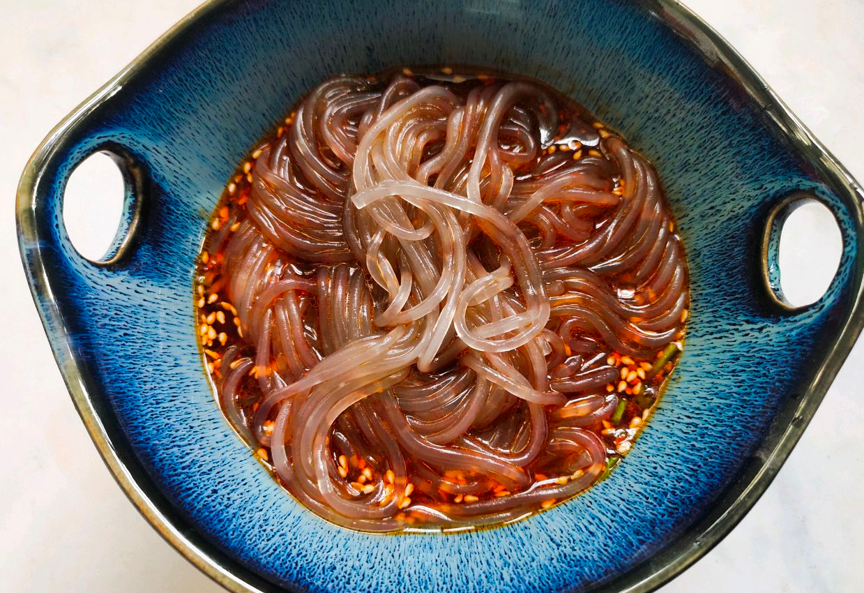 Combine cooked sweet potato noodles with prepared sauce in a bowl.