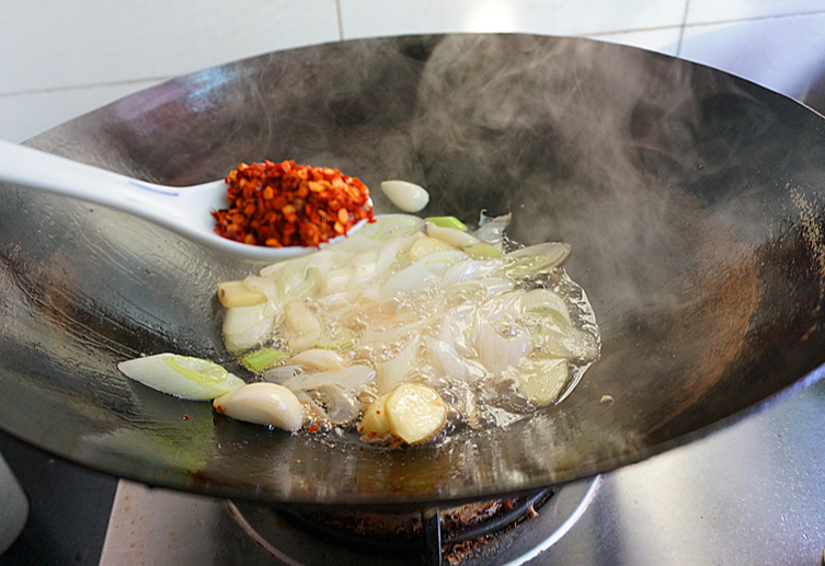 Add Sichuan peppercorns and chili powder to the wok for a spicy kick.