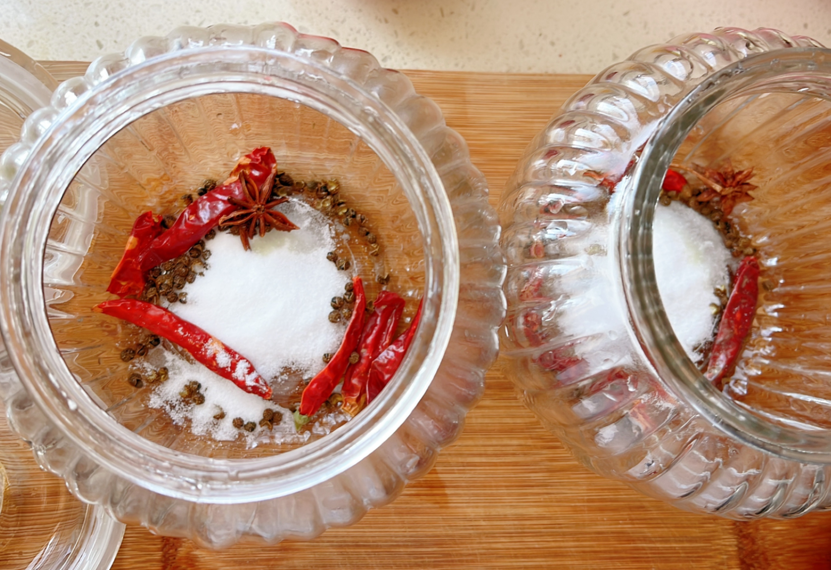 Prepare glass jars by washing and sanitizing. Add star anise, salt, peppercorns, chili peppers, and vinegar.