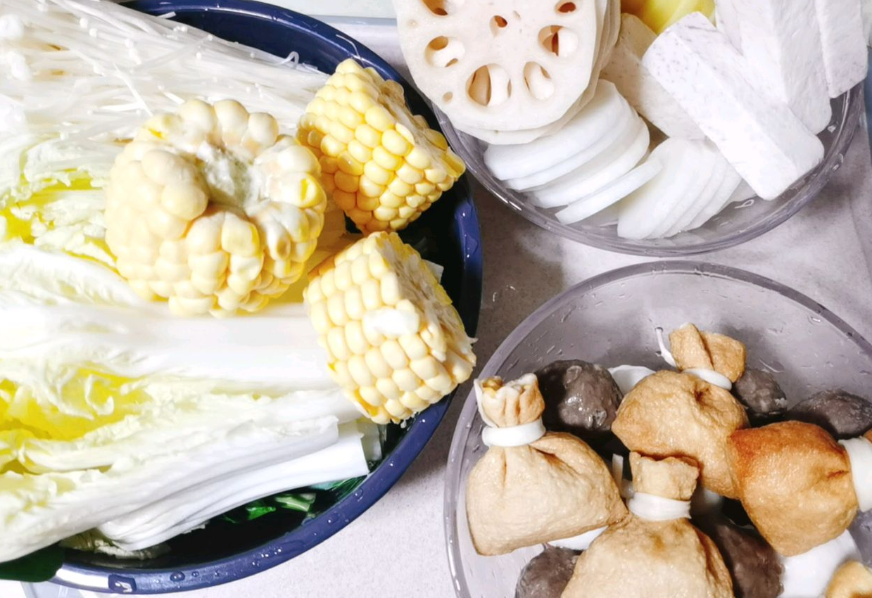 Prepare additional hot pot ingredients: corn, enoki mushrooms, bok choy, lotus roots, and hot pot balls.