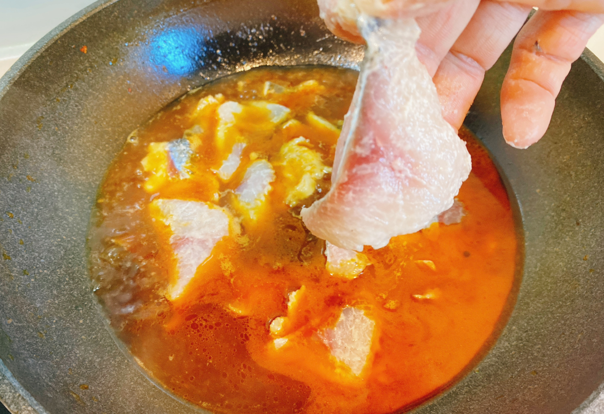 Cook fish slices in low heat with red oil broth in a wok.