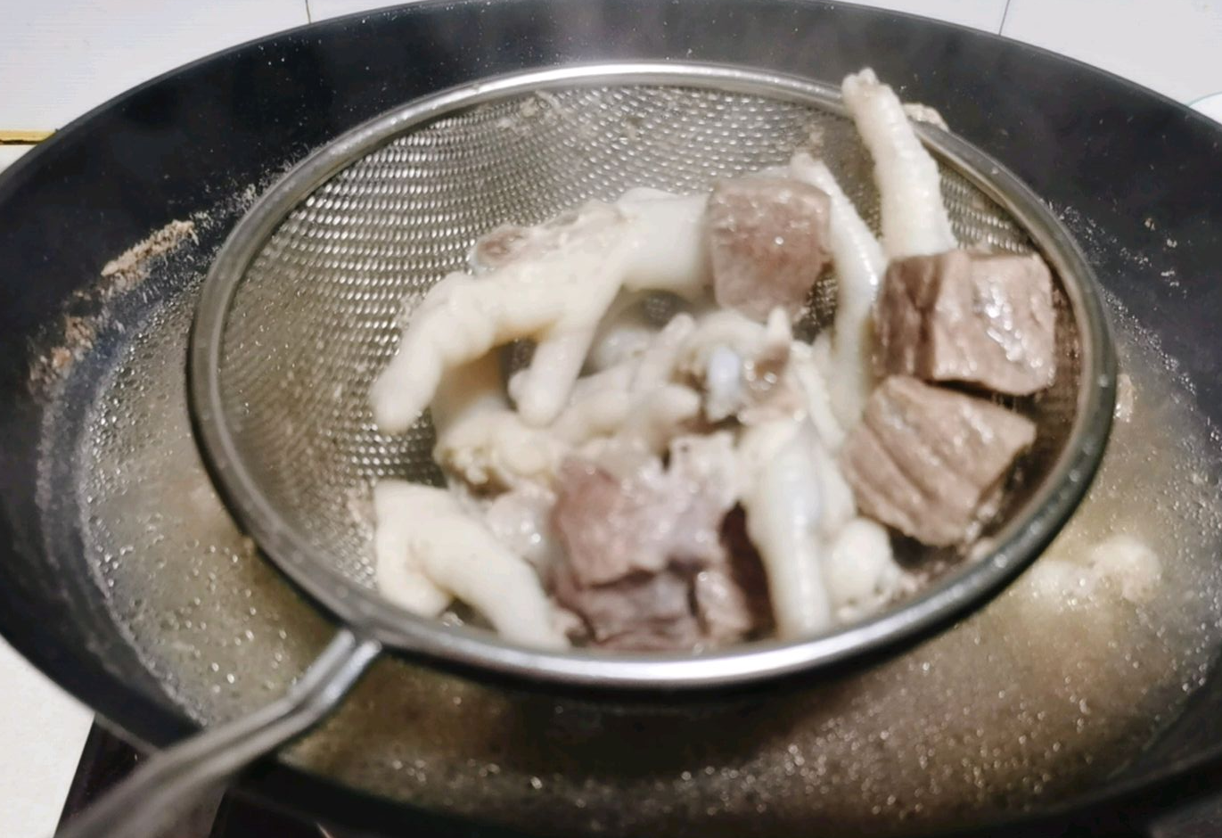 Clean blanched meat by rinsing beef and chicken feet under cold water after blanching.