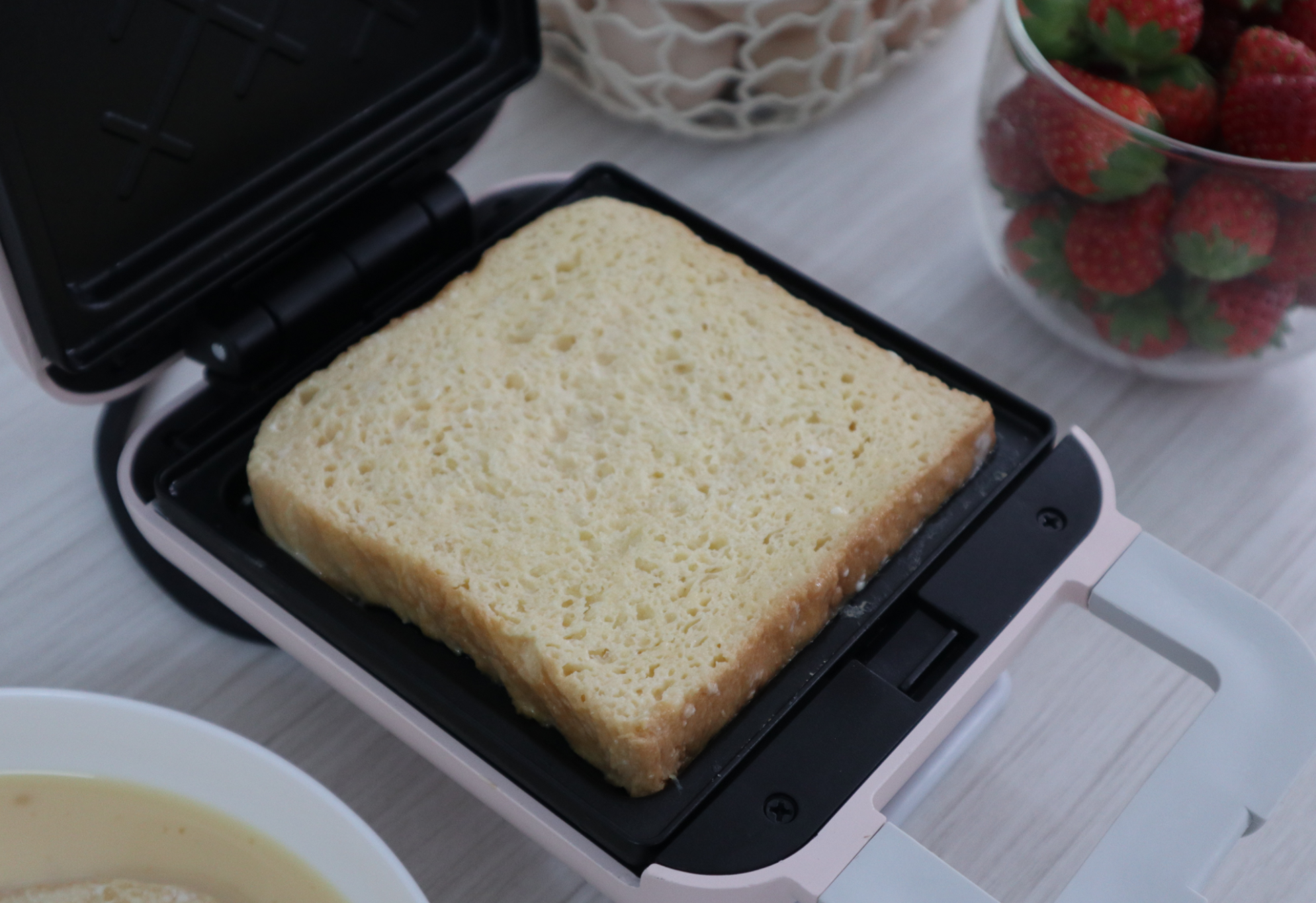 Preheat sandwich maker, add butter, place soaked bread slice inside.