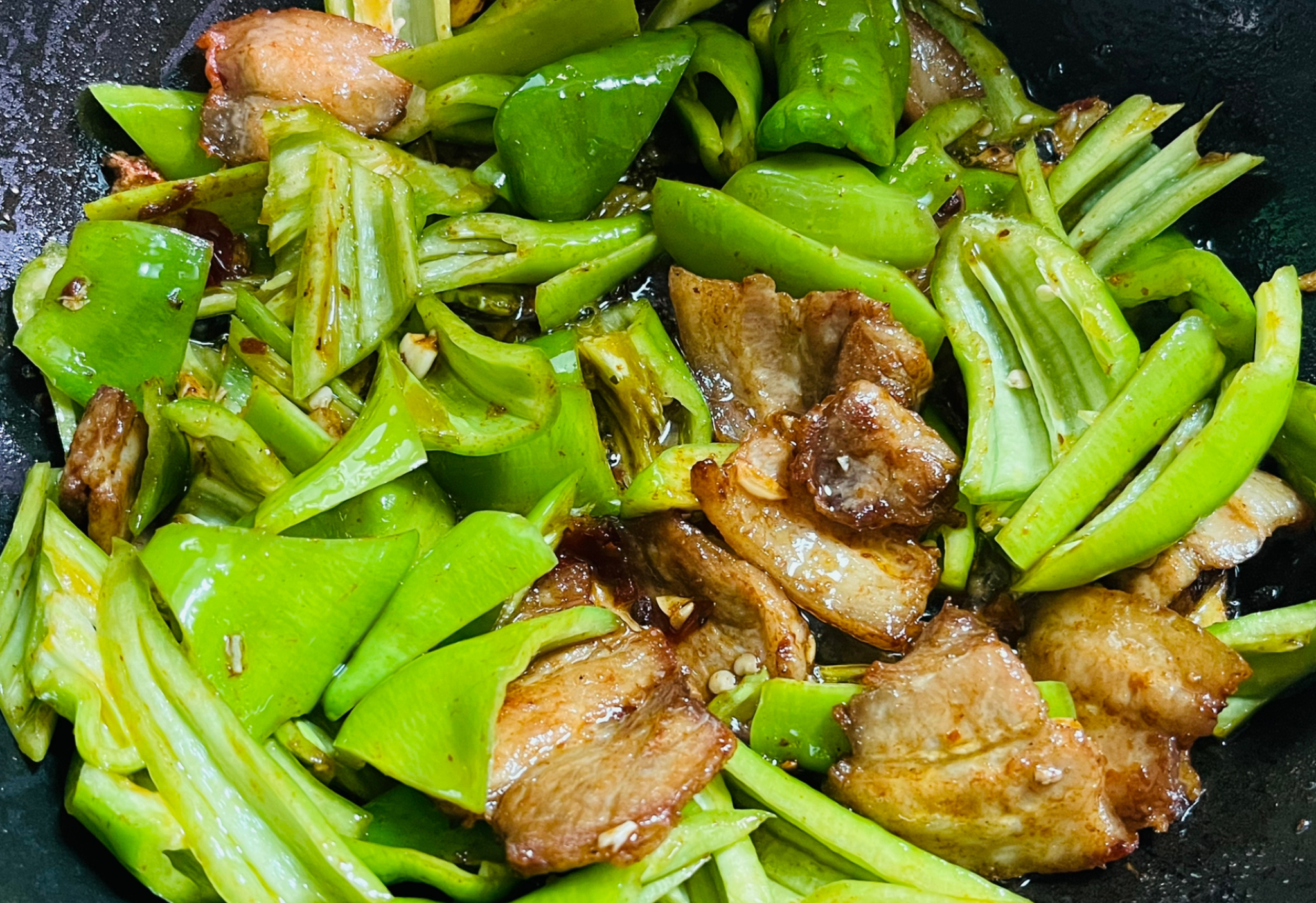 Add green peppers to fragrant, seasoned pork belly & stir-fry until cooked.